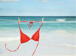 Женщина в красных стрингах, прикрыв грудь руками, бросилась купаться в море